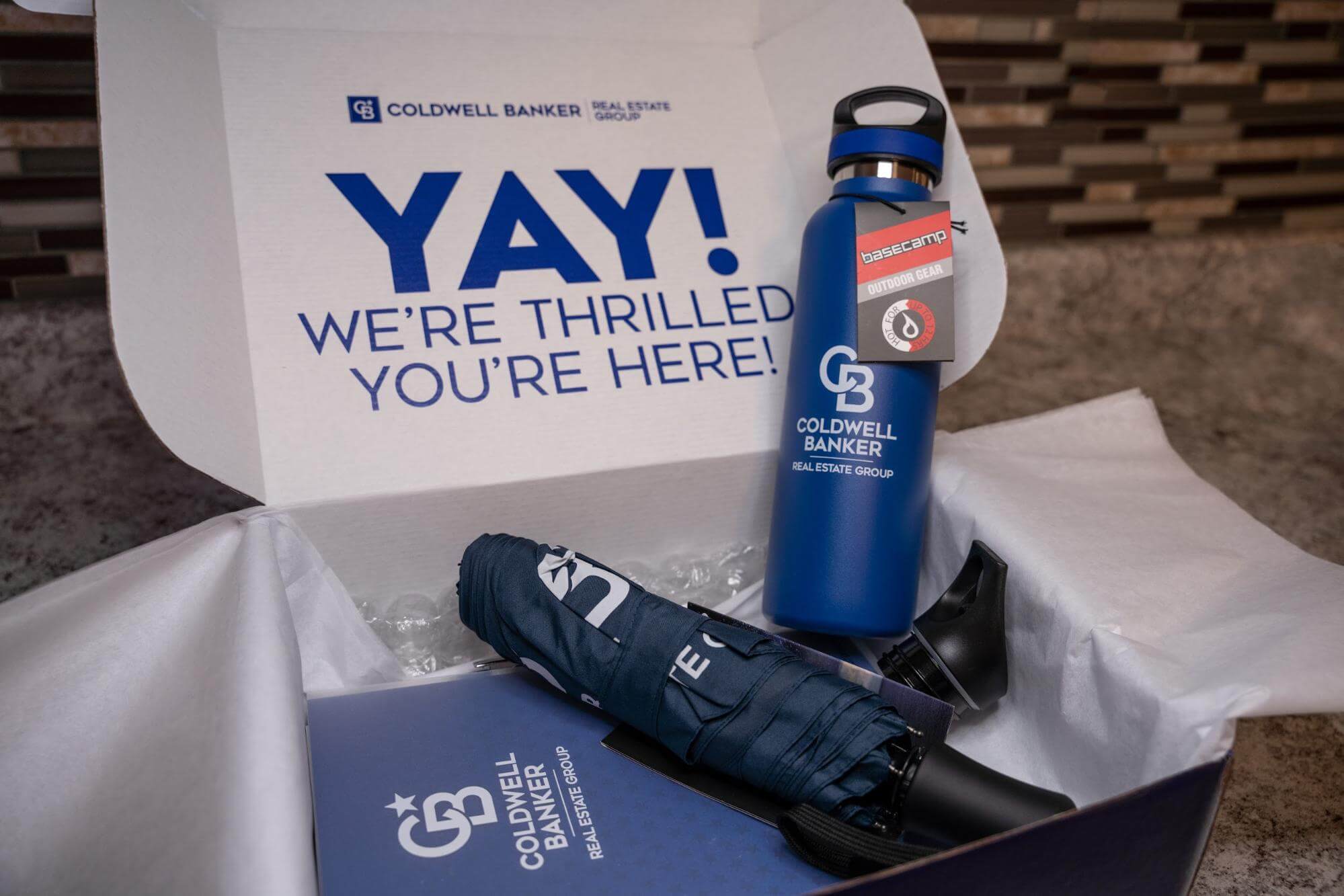 Employee welcome box for Coldwell banker featuring branded water bottle and other key items.